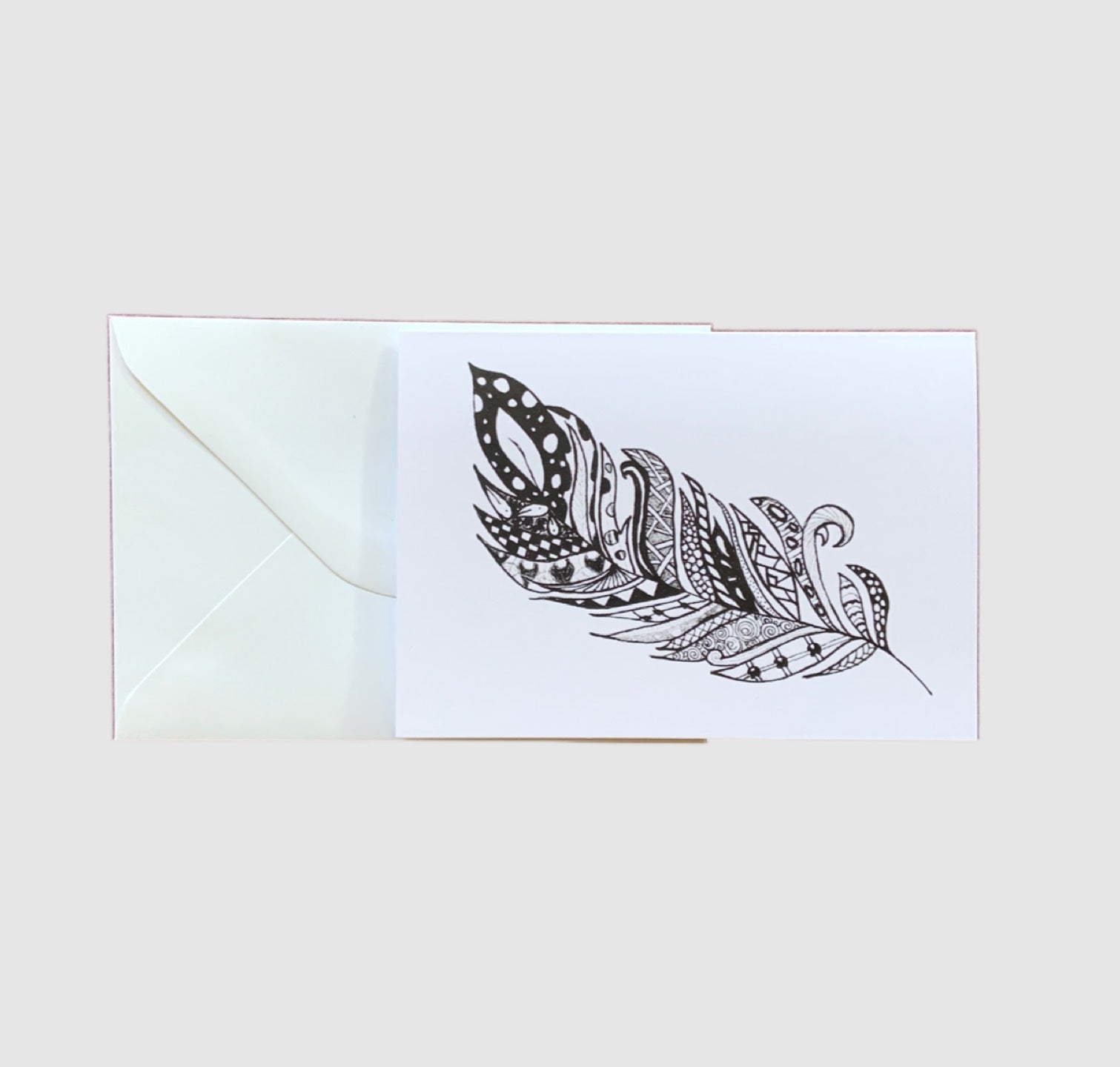 A sketch of a black and white zentangle feather on the front of a greeting card.