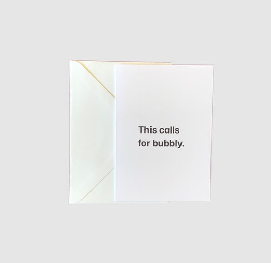 The words 'this calls for bubbly' on the front of a greeting card.