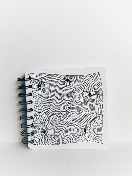 Front cover of a handmade journal showing black and white zentangle art.