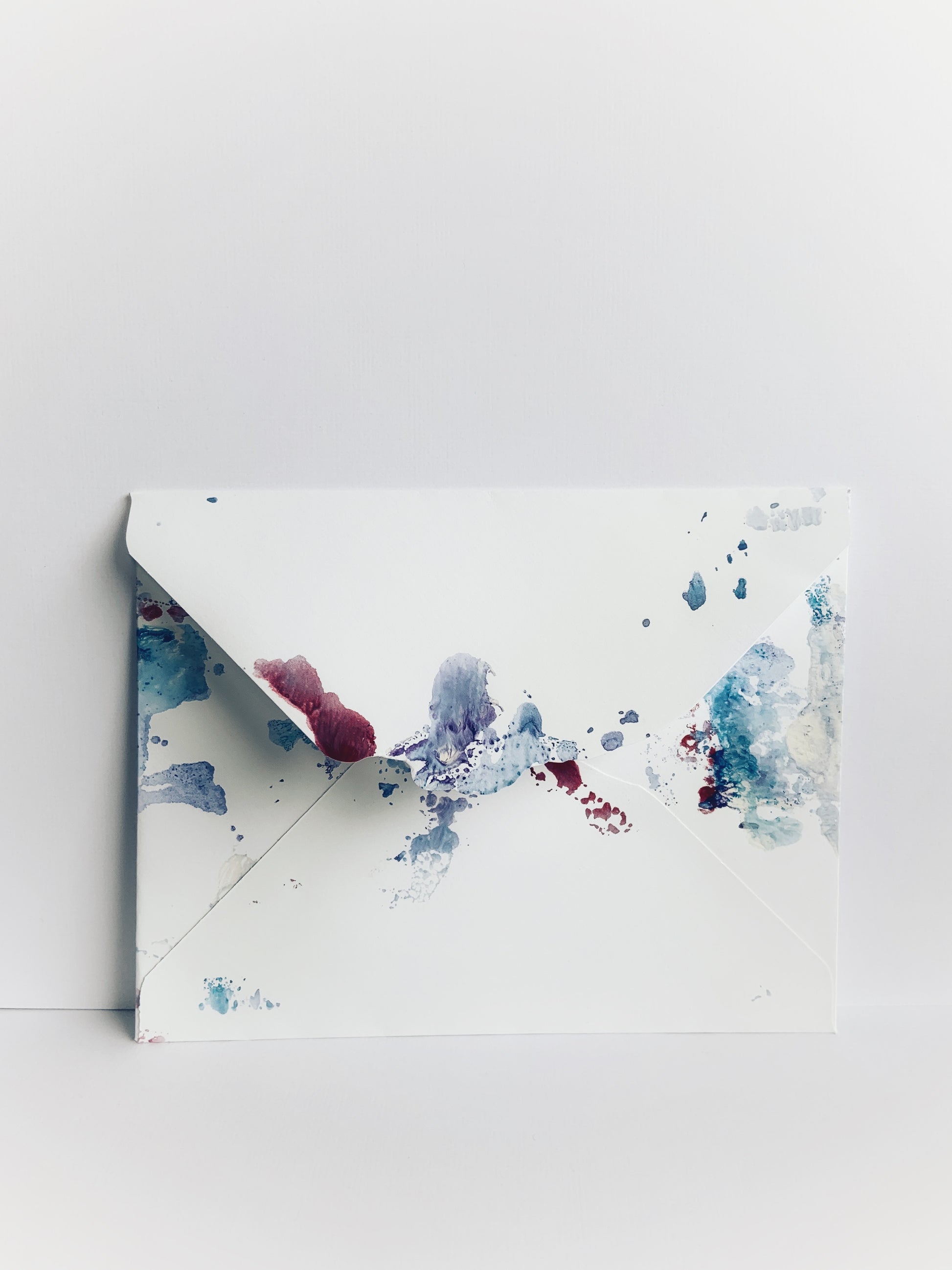 Envelope painted with soft blue and purple watercolor with scalloped detail on the back