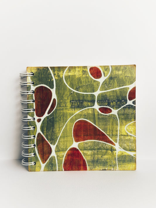 Front of painted handmade journal in chartreuse and red with white neurographic art