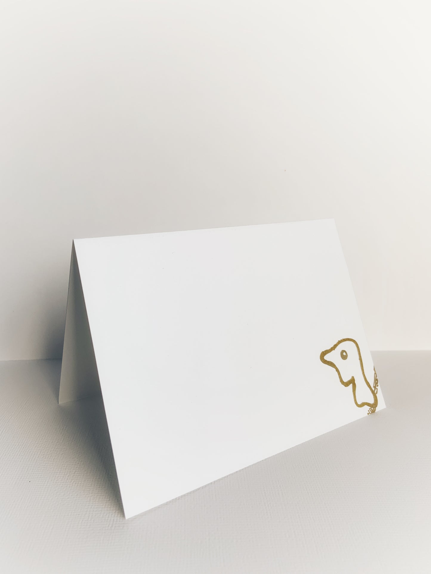 Front of a white handmade envelope made out of cardstock with a little dolphin drawn with a gold felt marker in one corner.