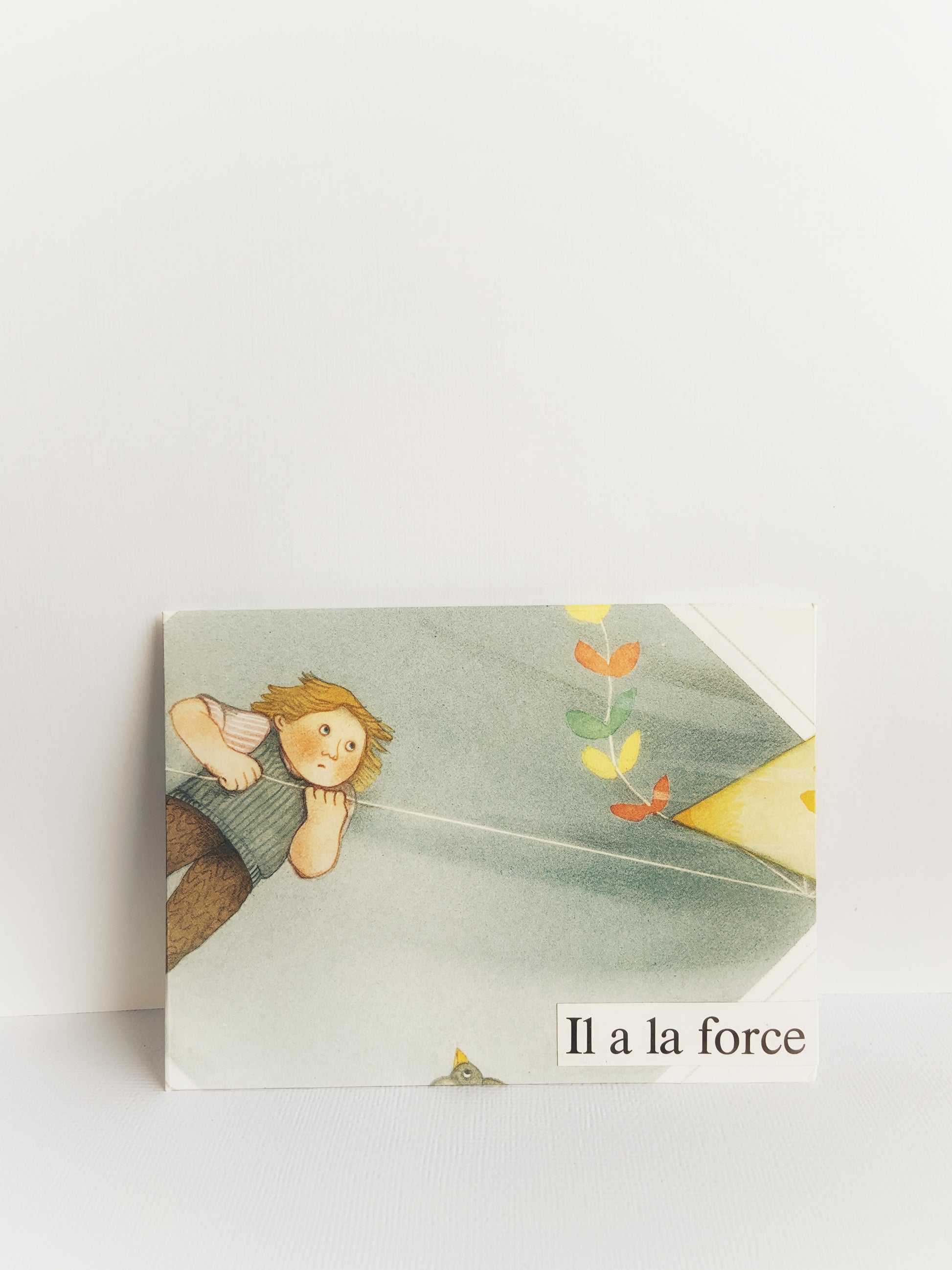 The front of a handmade envelope that has a young boy on the front flying a colorful kite and has 'Il a la force' on the bottom.