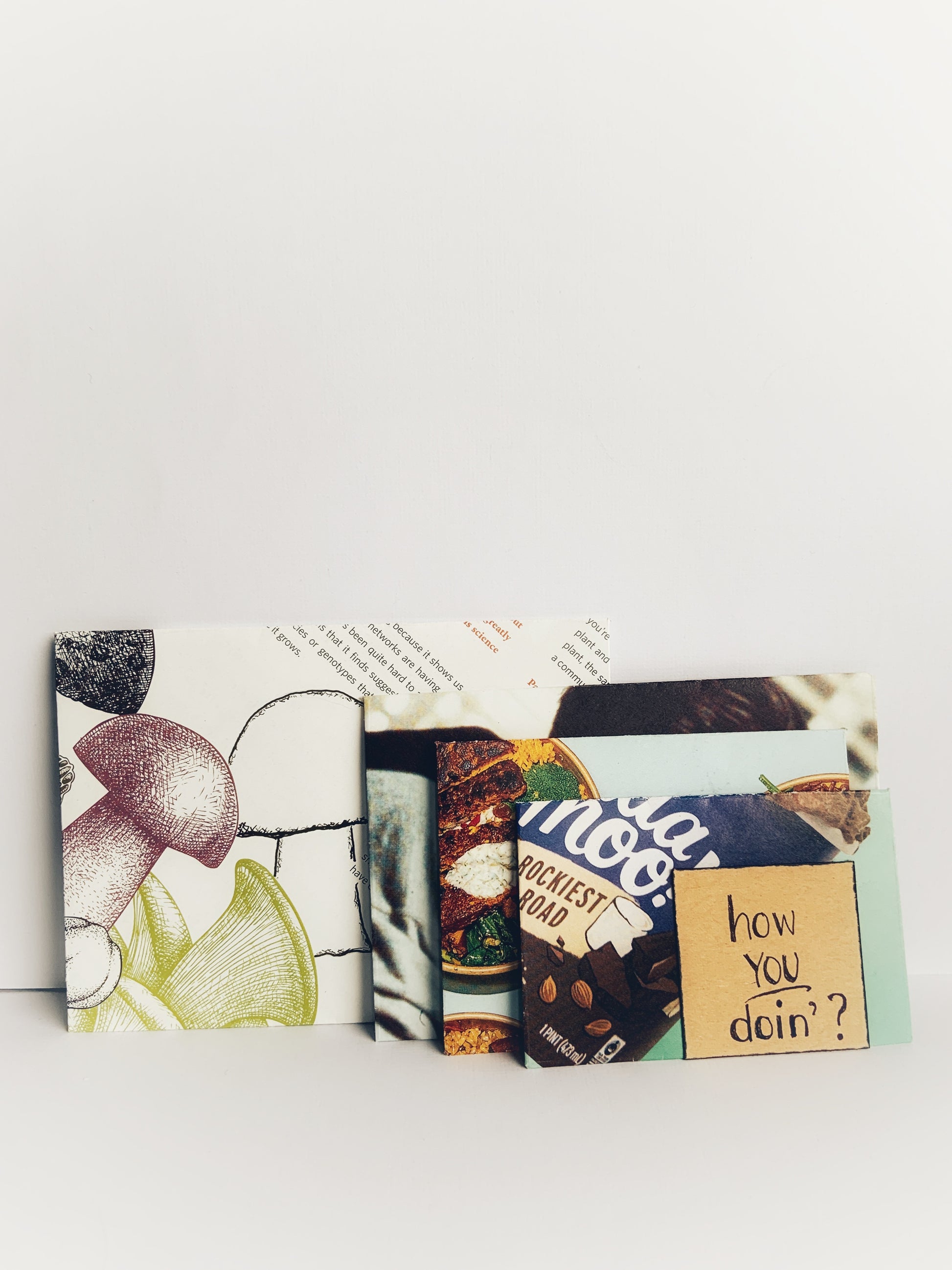 Handmade nesting envelopes made from magazine pages with a note saying how you doin'?