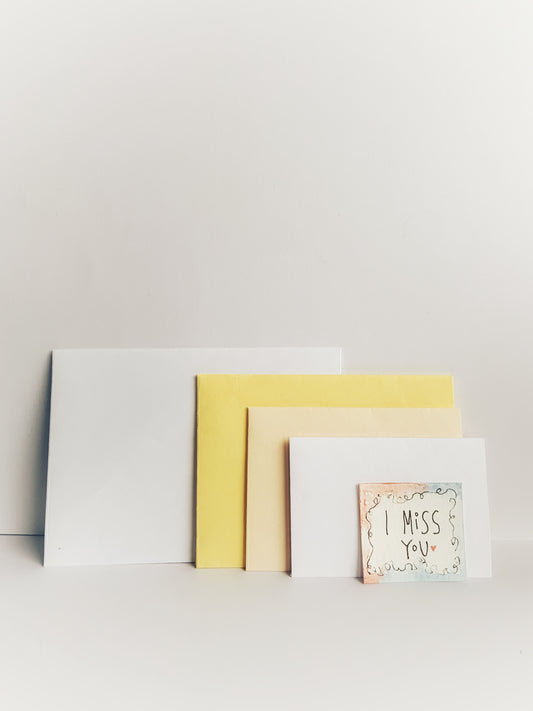 Handmade nesting envelopes in plain white and yellow with a note saying I miss you.