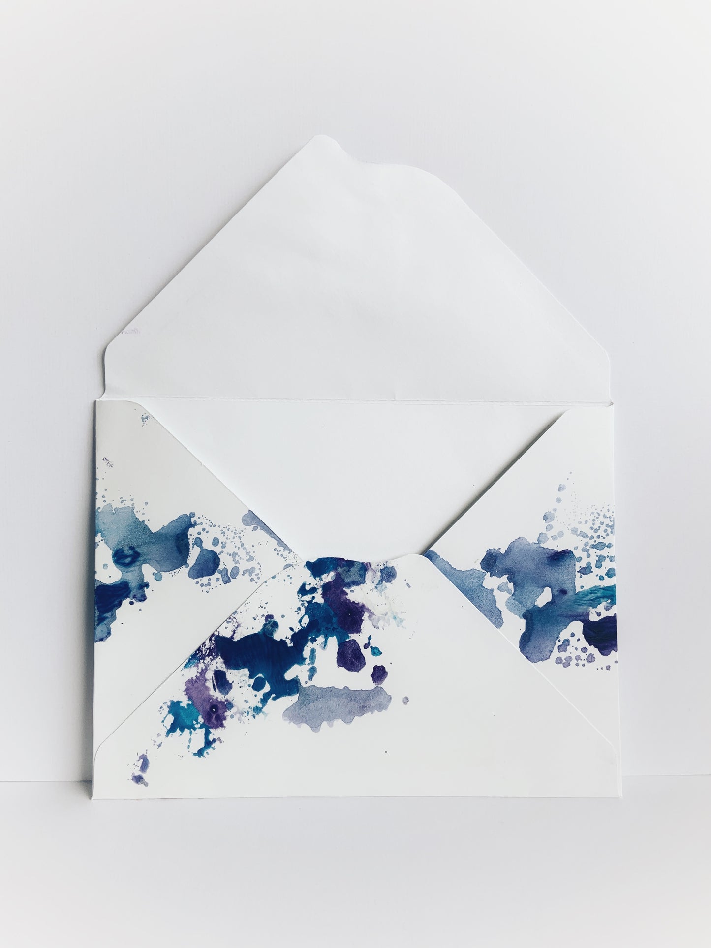 The back of a handmade envelope showing a scalloped flap and blue and red watercolor