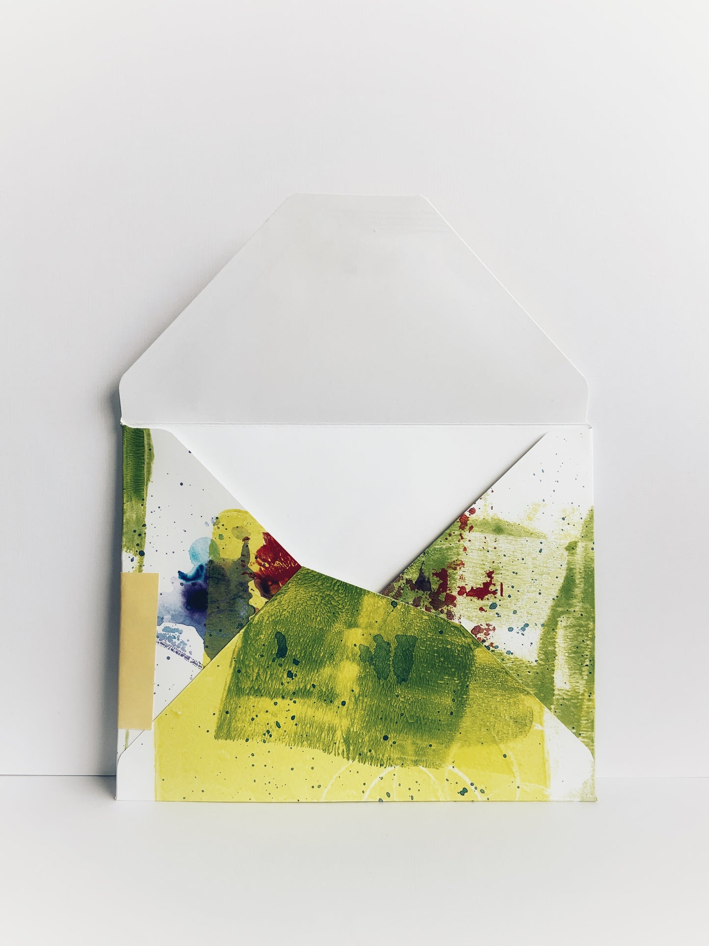 Back of an envelope with irregular design and abstract paint in green, yellow and red