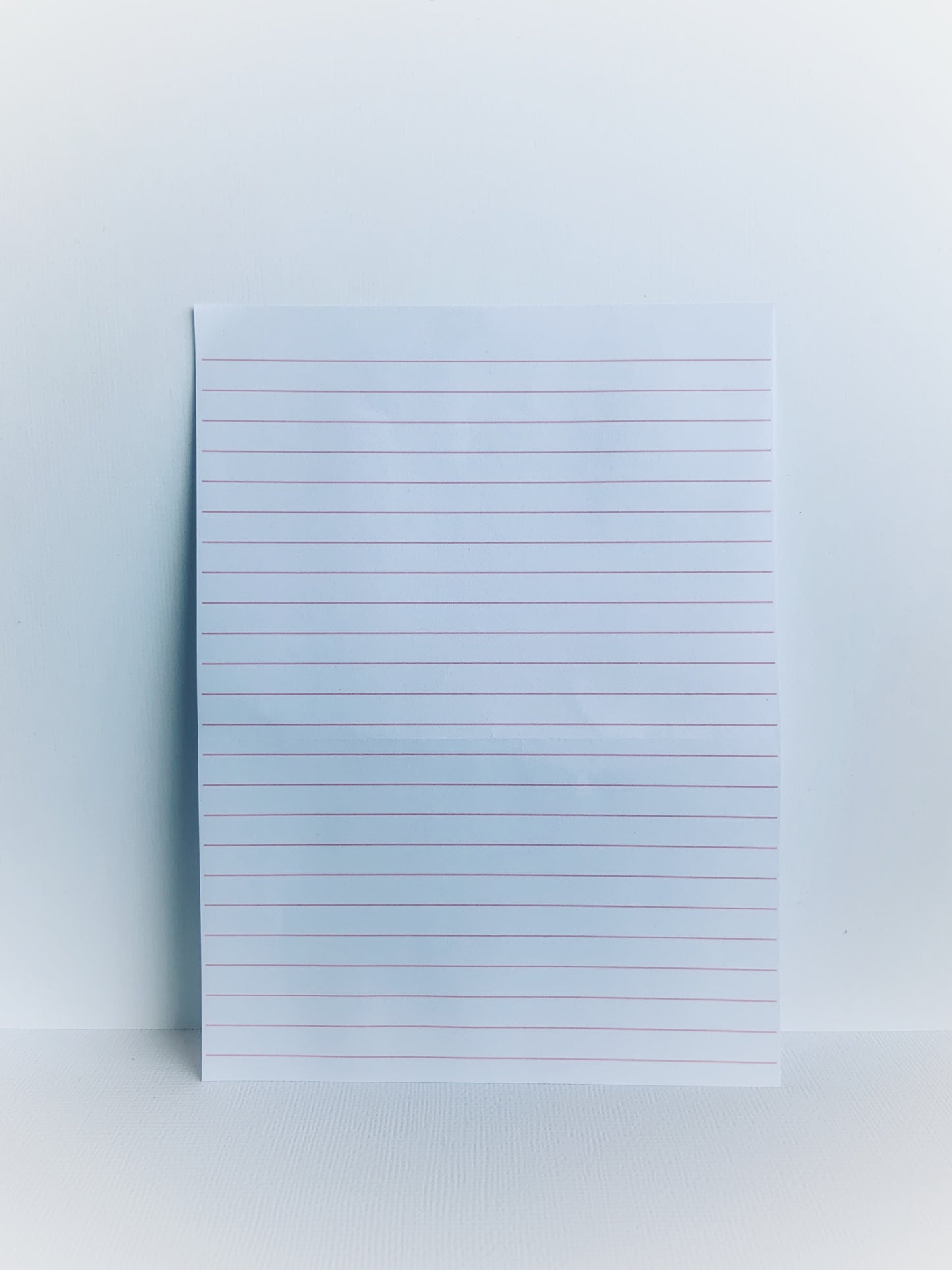 Mauve notepaper with pink lines.