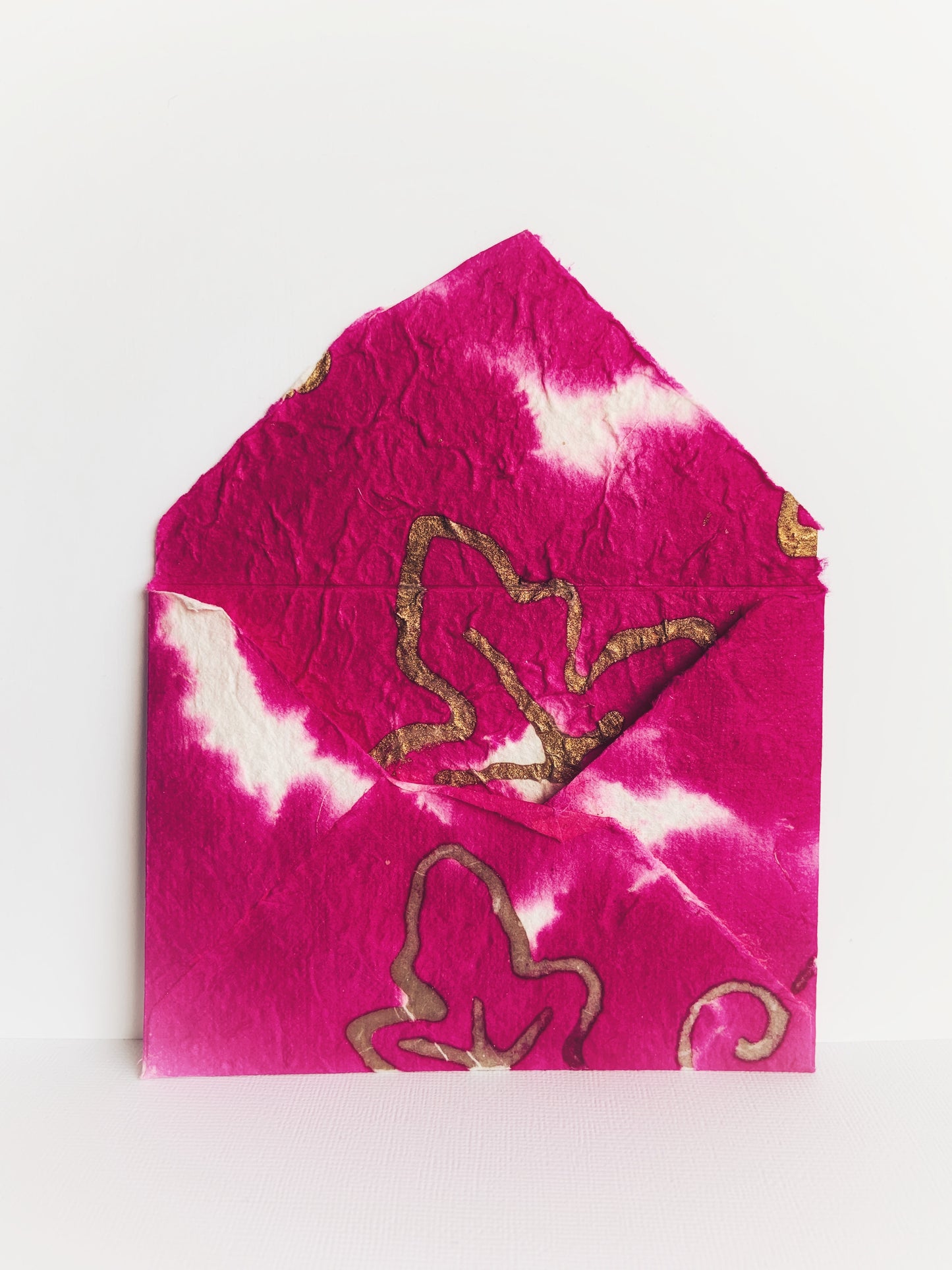 Back of handmade envelope made from pink handmade paper with gold leaf from Thailand showing detail on inside and flap.