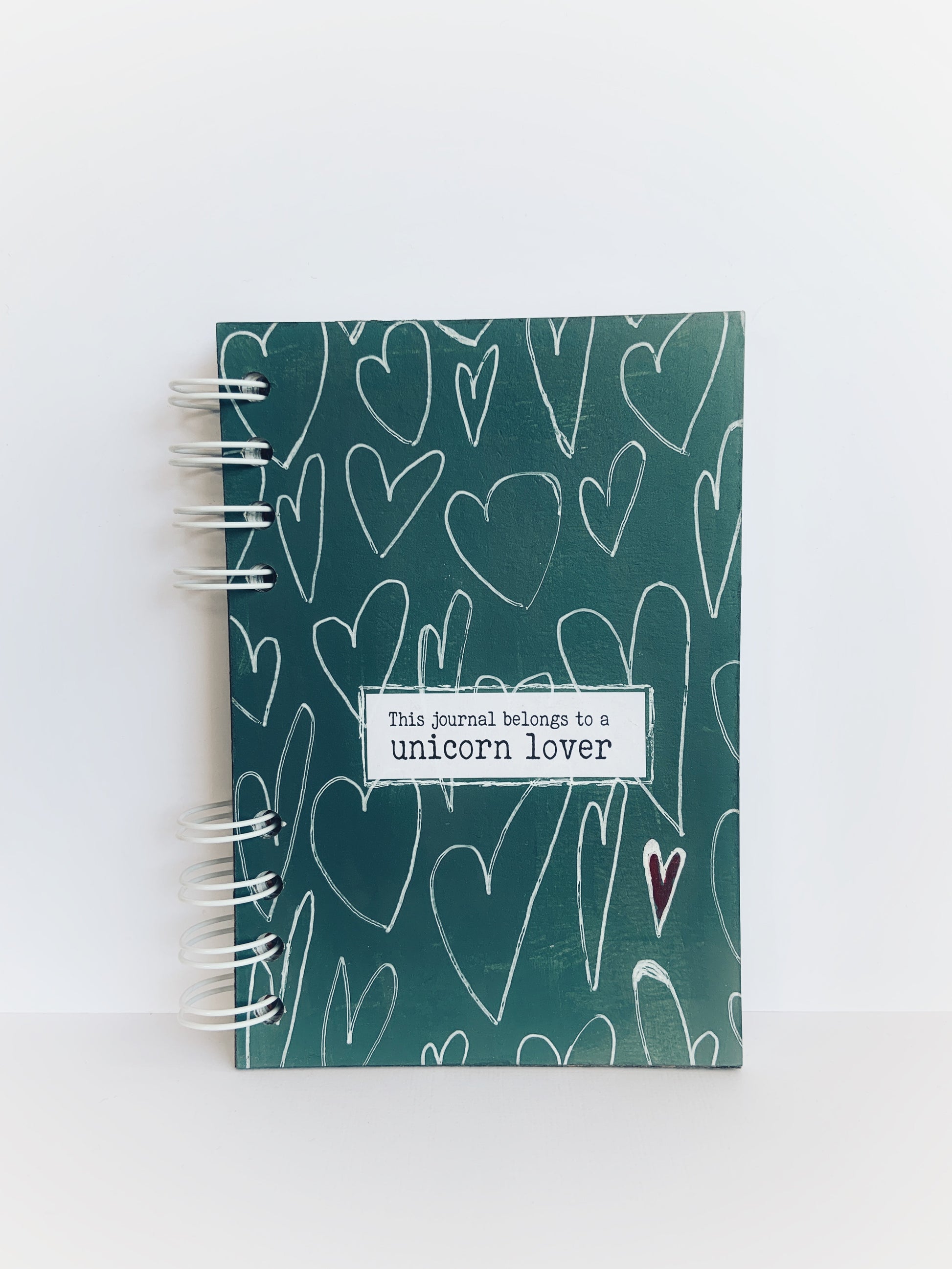 Front cover of a handmade lined journal with white hearts and 'This Journal Belongs to a Unicorn Lover'