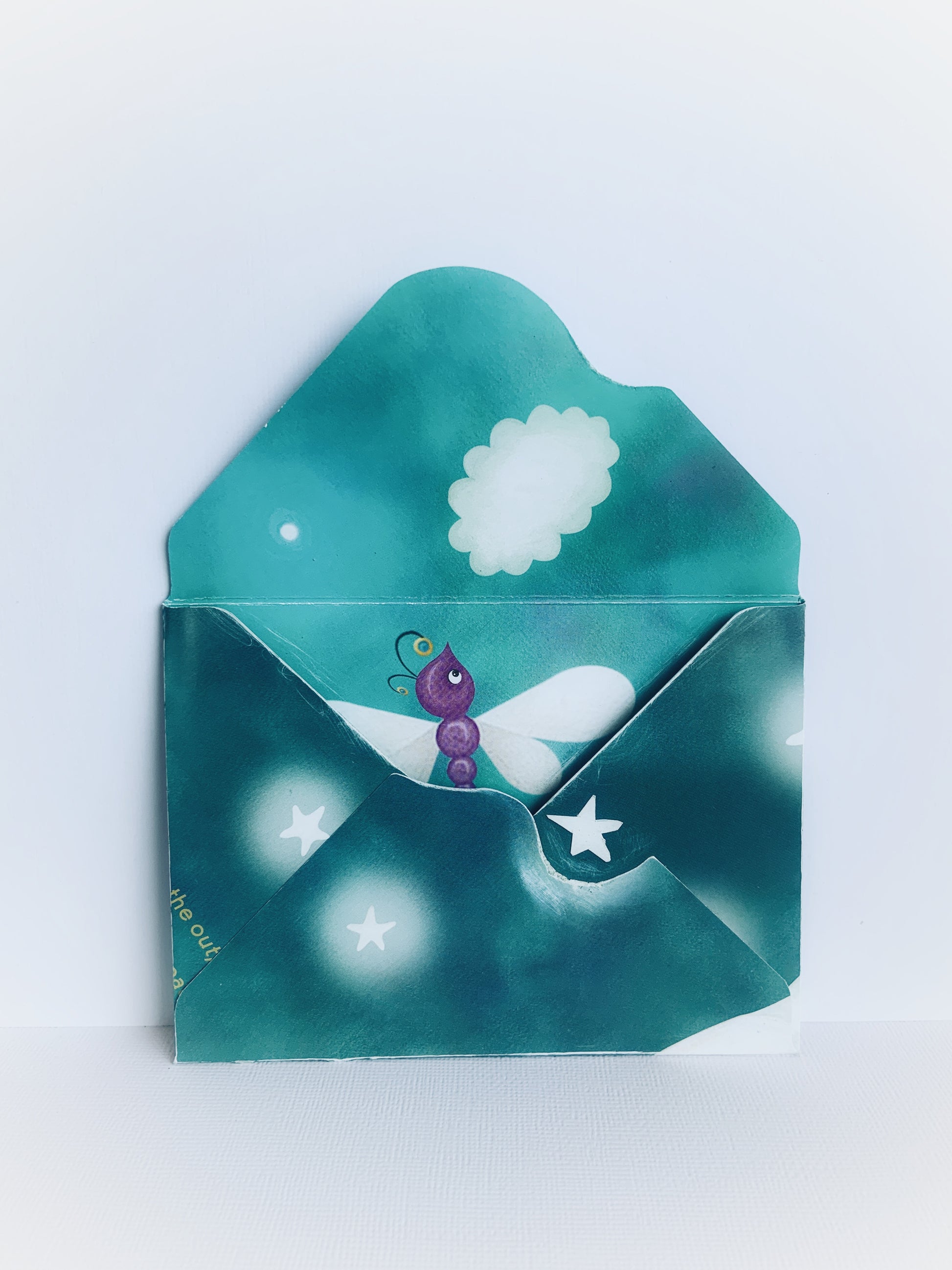 The back of a handmade children's envelope with a purple dragonfly, a cloud and stars that shows the detail on the inside and on the flap.