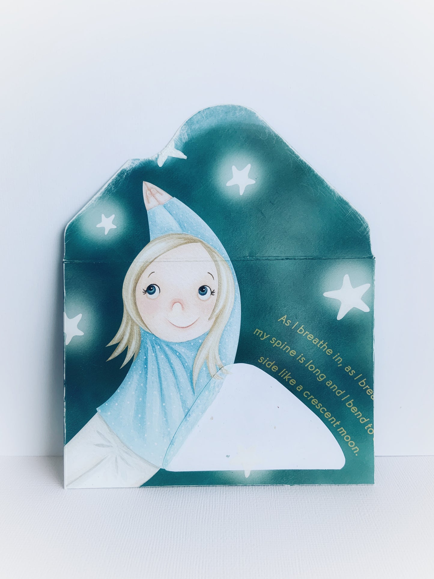 The front of a handmade children's envelope with a little girls with her arms up bending to the side and stars around her and words about breathing and looking like a crescent moon.